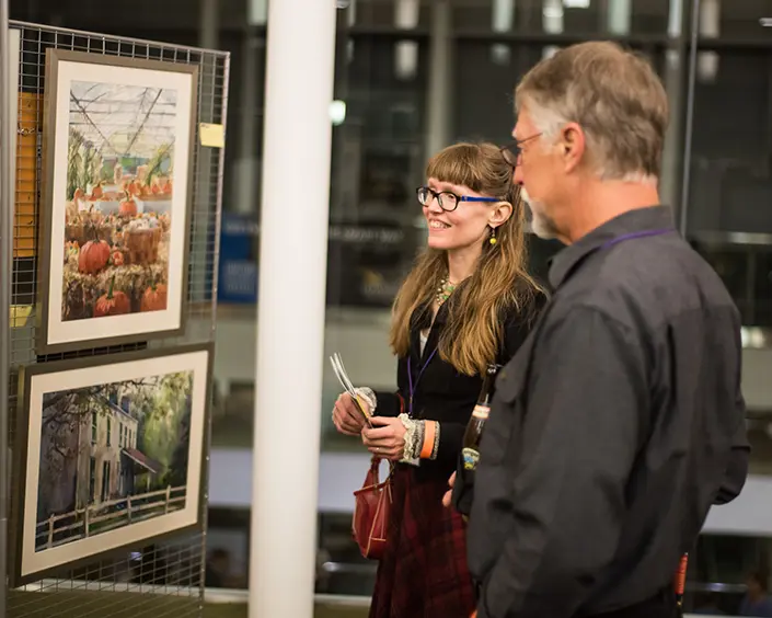 two artists discussing pictures hung up in a galary